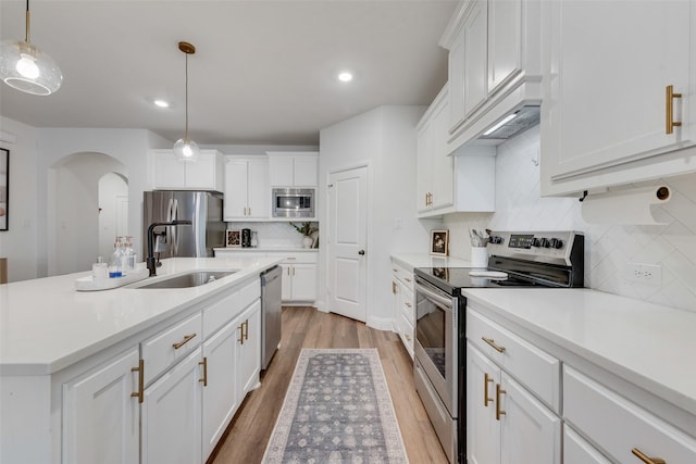 kitchen with tasteful backsplash, stainless steel appliances, white cabinets, and hanging light fixtures