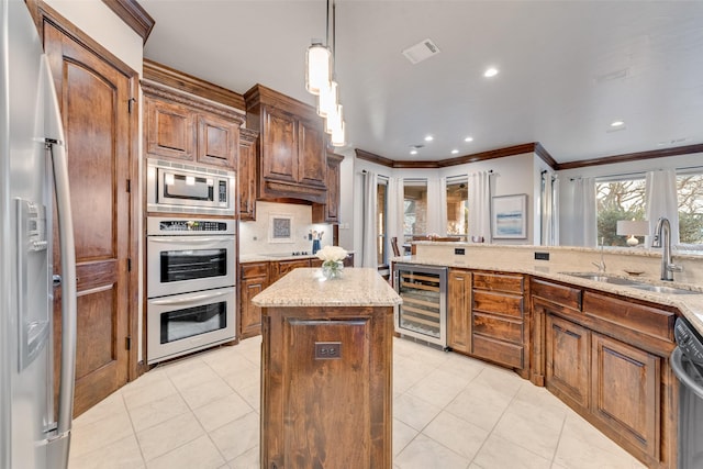 kitchen featuring beverage cooler, stainless steel appliances, a center island, sink, and decorative light fixtures