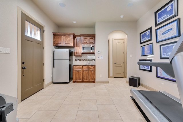 kitchen with stainless steel appliances, light tile patterned floors, backsplash, and sink