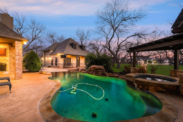 pool at dusk with a patio and an in ground hot tub