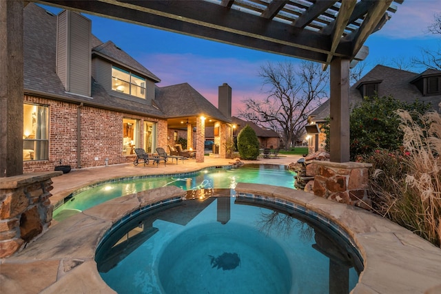 pool at dusk with a patio, an in ground hot tub, and a pergola