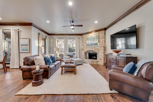 living room featuring a fireplace, ceiling fan, crown molding, and hardwood / wood-style floors