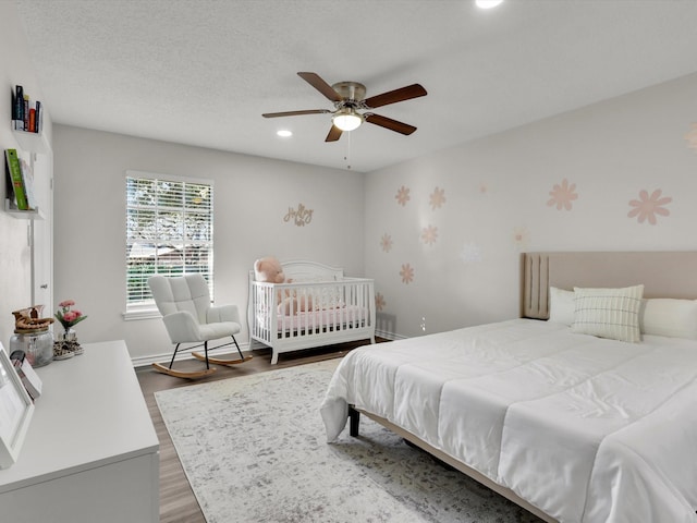 bedroom featuring dark hardwood / wood-style flooring, a textured ceiling, and ceiling fan