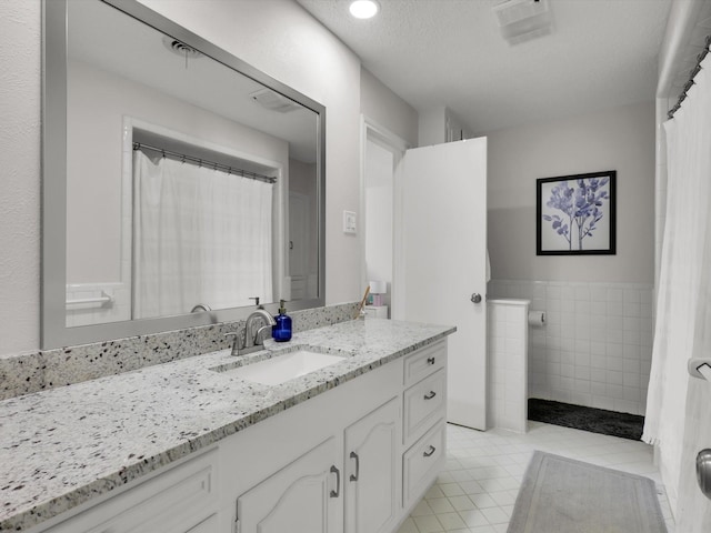 bathroom with a textured ceiling, tile patterned floors, and vanity