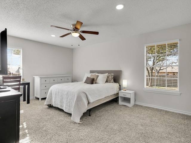 carpeted bedroom featuring ceiling fan and a textured ceiling