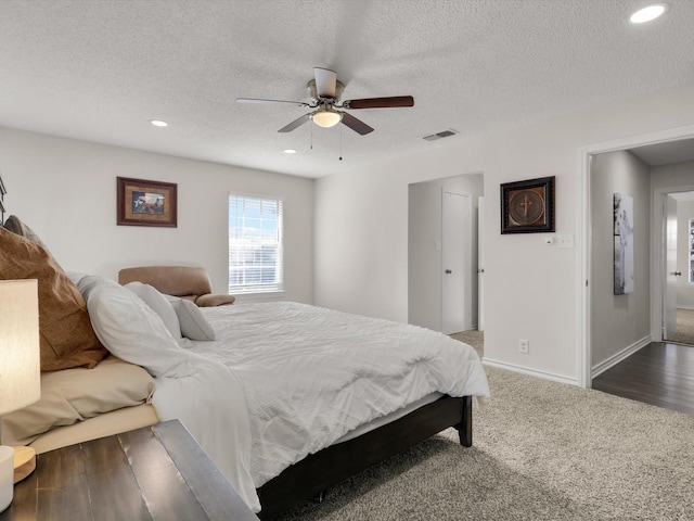 bedroom with a textured ceiling, ceiling fan, and dark colored carpet