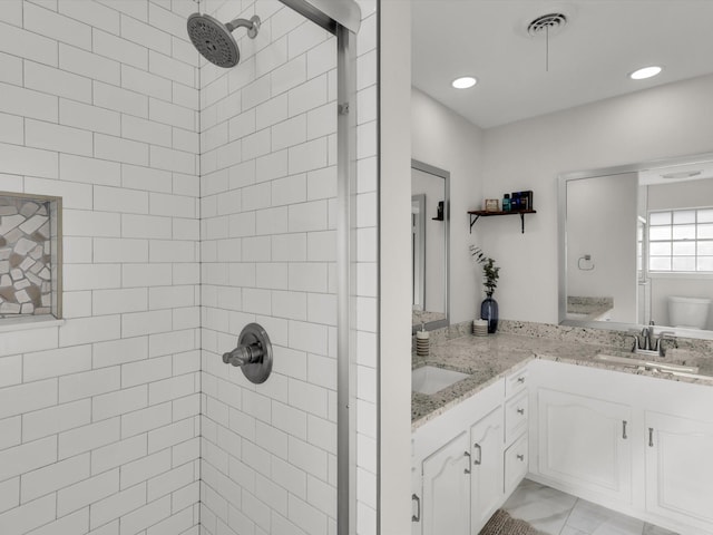 bathroom with a tile shower, vanity, and toilet