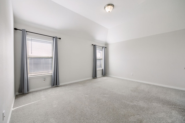 carpeted empty room with lofted ceiling