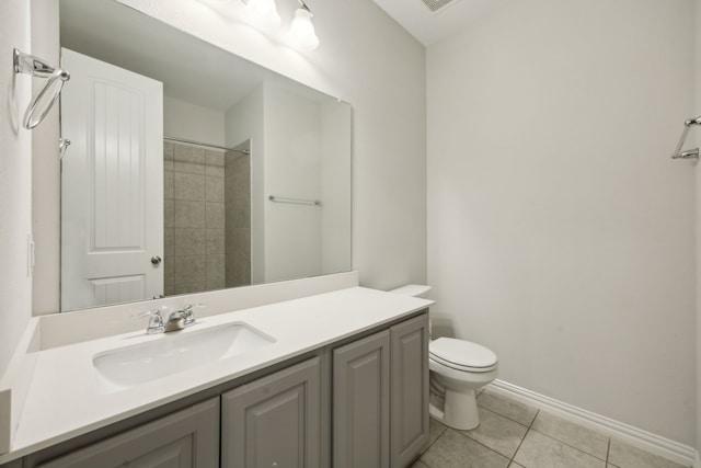 bathroom featuring toilet, a tile shower, vanity, and tile patterned floors