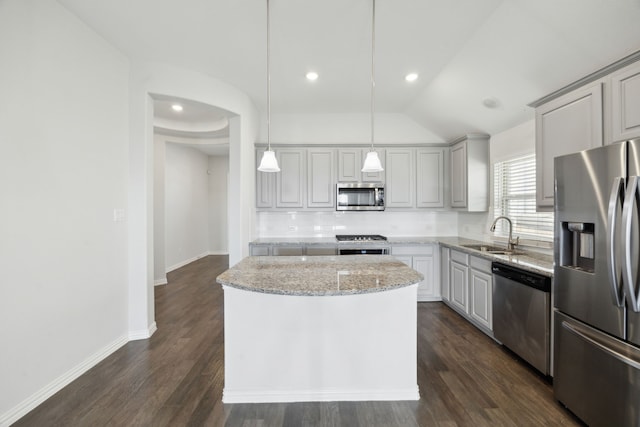 kitchen with stainless steel appliances, hanging light fixtures, a kitchen island, sink, and tasteful backsplash