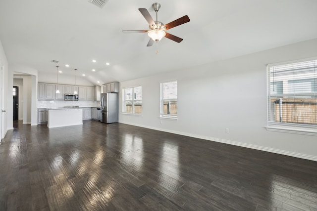 unfurnished living room featuring ceiling fan, a healthy amount of sunlight, and dark hardwood / wood-style floors