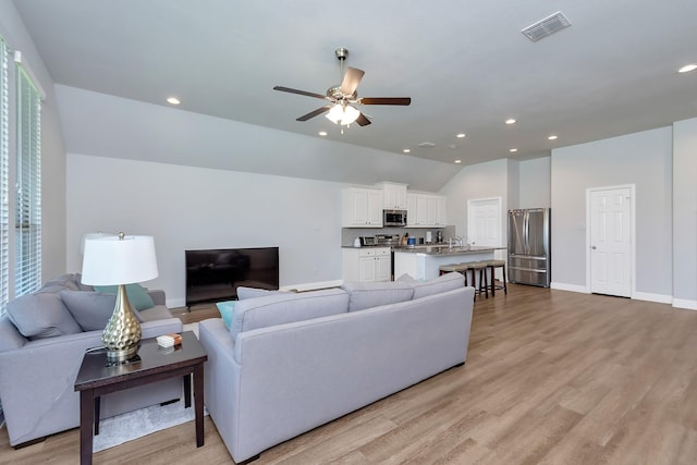 living room featuring light hardwood / wood-style floors, ceiling fan, and lofted ceiling