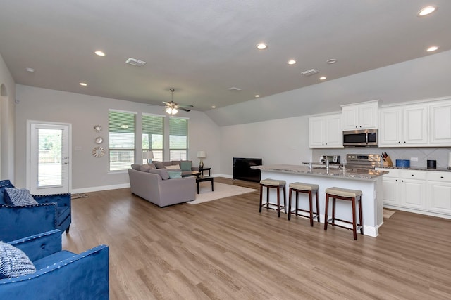 living room featuring ceiling fan, light hardwood / wood-style flooring, and lofted ceiling