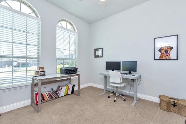 office space featuring light colored carpet, vaulted ceiling, and a wealth of natural light