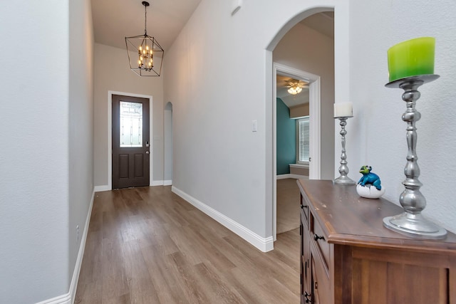 foyer entrance featuring light hardwood / wood-style flooring, vaulted ceiling, and ceiling fan with notable chandelier