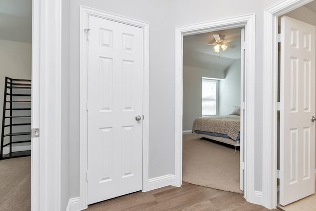 hallway with light wood-type flooring and vaulted ceiling