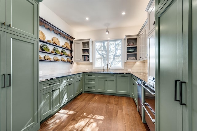 kitchen featuring green cabinetry, paneled fridge, decorative backsplash, and light stone counters