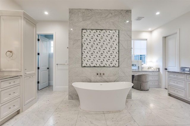 bathroom with tile walls, a bathtub, and vanity