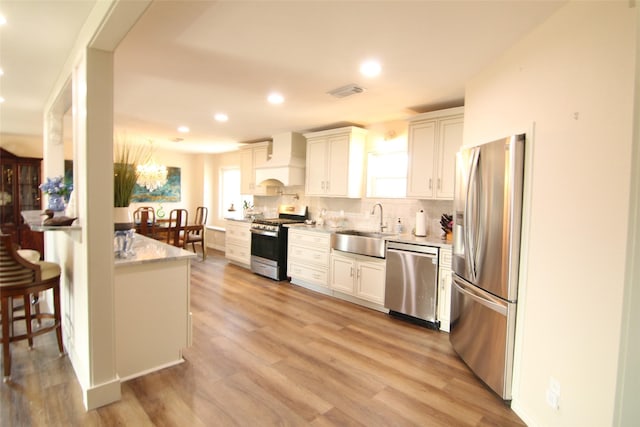 kitchen featuring sink, stainless steel appliances, white cabinetry, and custom exhaust hood