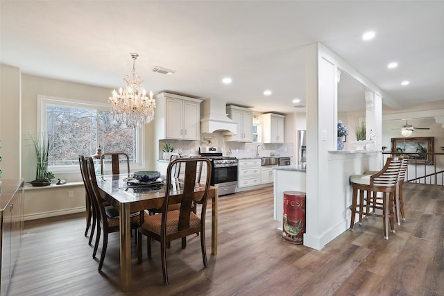 dining space featuring ceiling fan with notable chandelier, dark hardwood / wood-style floors, and sink