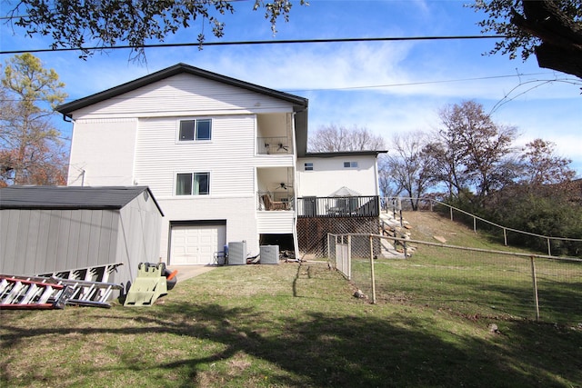 back of property with a balcony, a garage, cooling unit, and a lawn