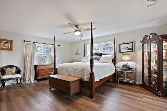 bedroom with ceiling fan, dark hardwood / wood-style flooring, and multiple windows