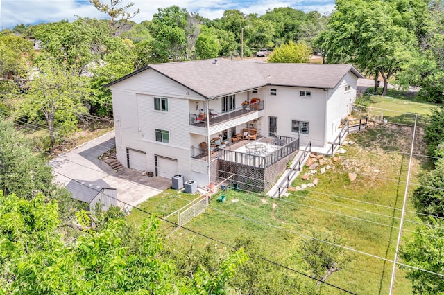 rear view of property featuring a chimney, a fenced backyard, a balcony, central air condition unit, and an attached garage