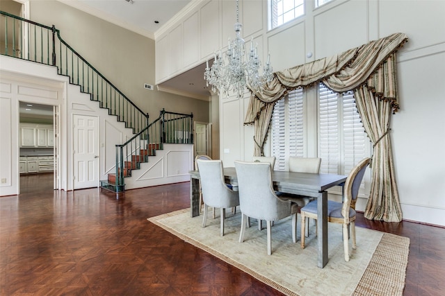 dining room with a towering ceiling, crown molding, and dark parquet floors