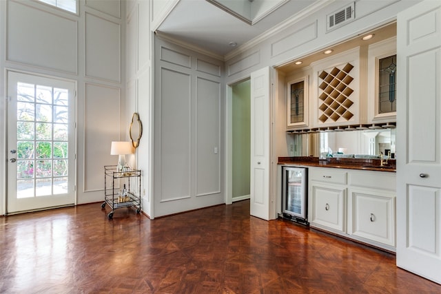 bar featuring dark parquet flooring, wine cooler, white cabinetry, ornamental molding, and sink