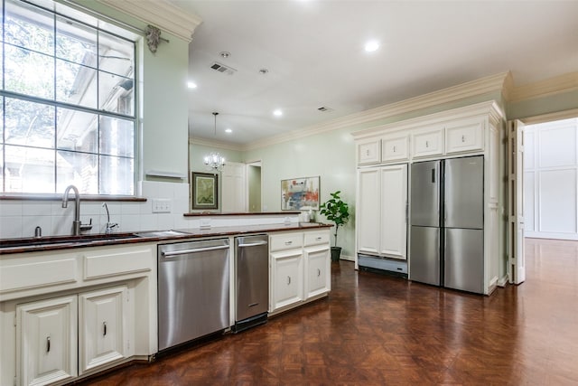 kitchen featuring decorative light fixtures, white cabinetry, appliances with stainless steel finishes, dark parquet floors, and sink