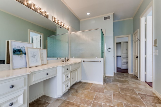 bathroom with a shower with door, vanity, and crown molding