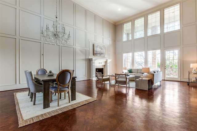 dining space featuring a towering ceiling, dark parquet flooring, and ornamental molding