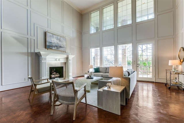 living room featuring a high ceiling, a fireplace, dark parquet floors, and crown molding