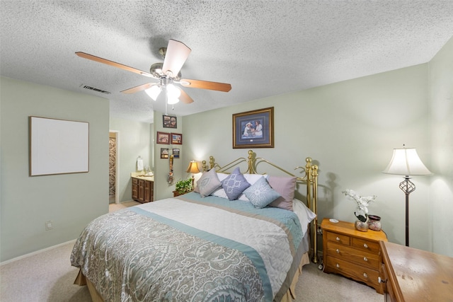 bedroom featuring light colored carpet, ceiling fan, a textured ceiling, and connected bathroom