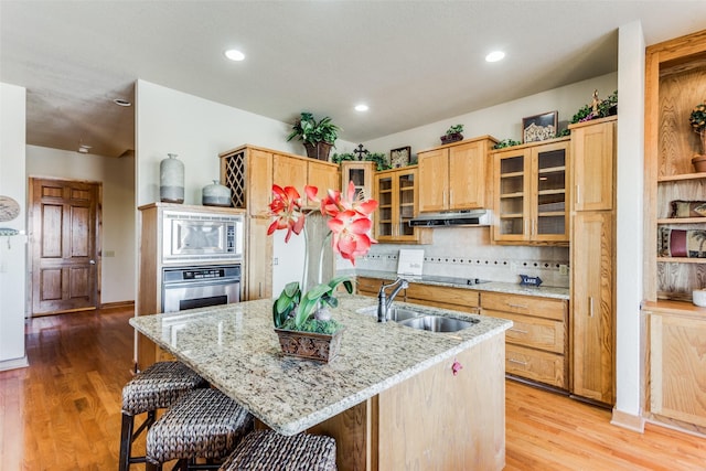 kitchen with a center island with sink, appliances with stainless steel finishes, light wood-type flooring, and sink