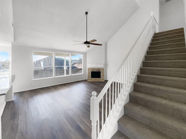 stairs featuring vaulted ceiling, a fireplace, ceiling fan, and hardwood / wood-style flooring