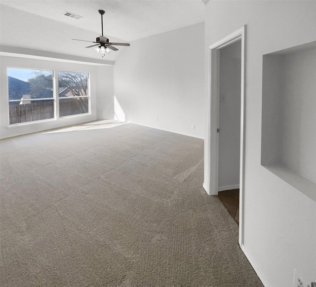 carpeted spare room with a textured ceiling, ceiling fan, and vaulted ceiling