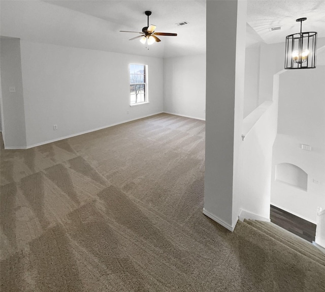 unfurnished room featuring ceiling fan with notable chandelier and carpet