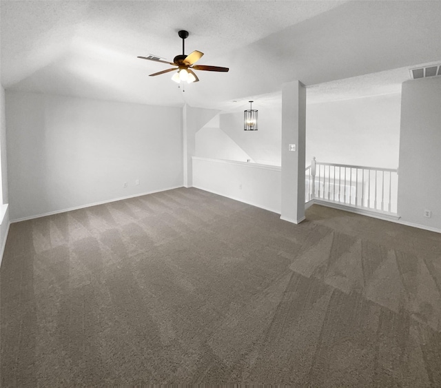 interior space featuring a textured ceiling, ceiling fan, and dark carpet