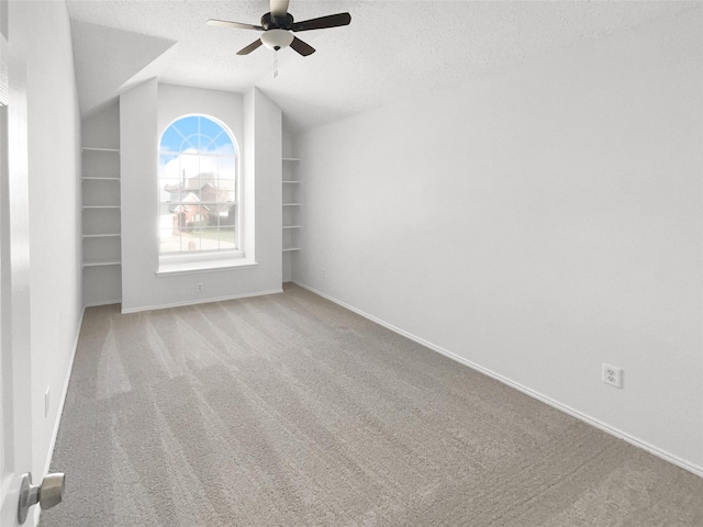 empty room featuring lofted ceiling, a textured ceiling, ceiling fan, and light colored carpet