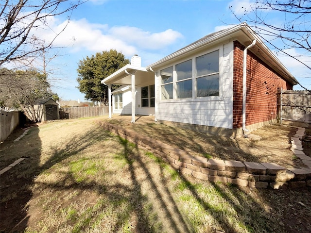 rear view of house with a storage unit and a lawn