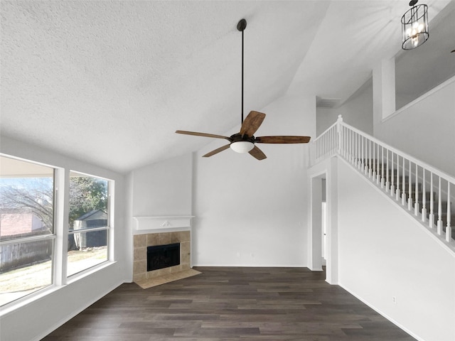 unfurnished living room featuring ceiling fan, a tile fireplace, vaulted ceiling, and dark hardwood / wood-style floors