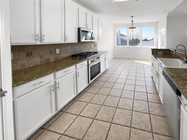 kitchen featuring stainless steel appliances, light tile patterned floors, backsplash, white cabinets, and sink