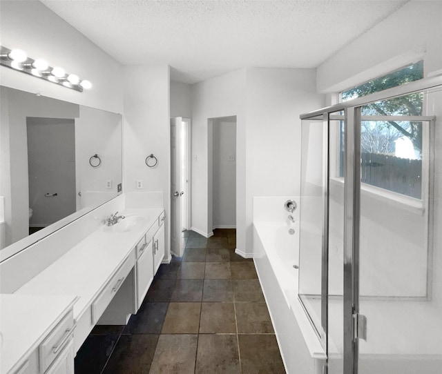 bathroom with a textured ceiling, independent shower and bath, and vanity