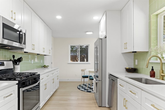 kitchen featuring stainless steel appliances, white cabinets, sink, and tasteful backsplash