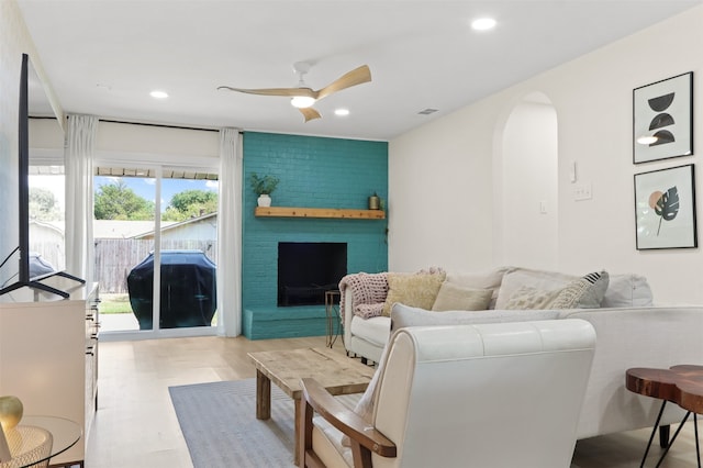 living room featuring ceiling fan and a brick fireplace