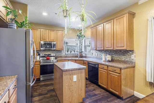 kitchen featuring dark wood-type flooring, a textured ceiling, stainless steel appliances, a kitchen island, and sink