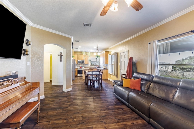 living room with ceiling fan with notable chandelier, a textured ceiling, crown molding, and dark hardwood / wood-style flooring