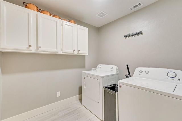 clothes washing area featuring cabinets and washing machine and clothes dryer