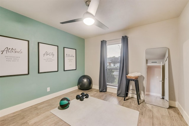 exercise room with ceiling fan and light hardwood / wood-style flooring